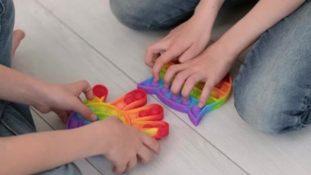 I bambini giocano con il giocattolo sensoriale pop it. ragazzo e ragazza premendo su colorate bolle di silicone morbido arcobaleno squishy. Stress e ansia. Trendy gioco di agitazione. Vista dall'alto. — Video Stock