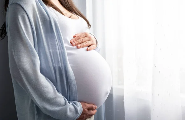 Здорова вагітність. Вид збоку вагітна жінка з великим черевом підвищена вагітність в руках. Банерна копія тексту. Елегантна мати чекає дитину . — стокове фото
