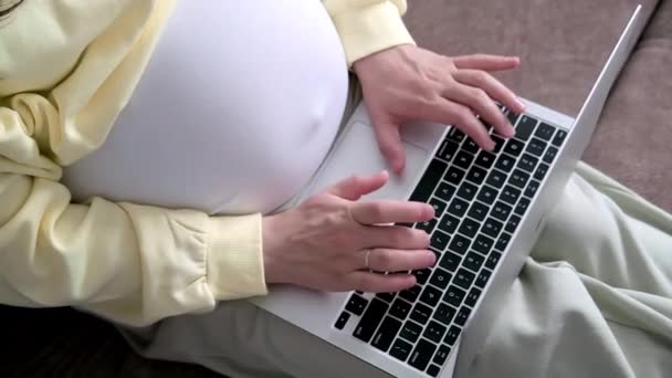 4k Top view Forventet mor arbejder eksternt online hjemmefra. Tæt på gravid ung kvinde hænder på bærbar computer med stor mave avanceret graviditet – Stock-video