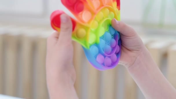Criança brincar com pop-lo brinquedo sensorial. Menino pressiona em colorido arco-íris squishy bolhas de silicone macio. Alívio de estresse e ansiedade. Jogo de alternância na moda para crianças e adultos estressados. — Vídeo de Stock