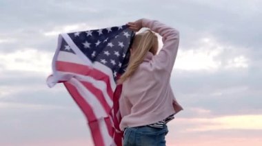 4 bin. Arkaya bakan sarışın kız plajda gün batımında gökyüzünde ulusal bayrak sallıyor - Amerikan bayrağı, ülke, vatanseverlik, bağımsızlık anıtı günü 4 Temmuz