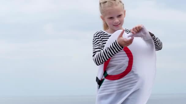 4k. Blondes Mädchen schwenkt Flagge bei den Olympischen Spielen im Freien über dem bewölkten Himmel bei Sonnenuntergang. Kindersportfan. Olympische Sommerspiele. 23.03.2020 St.Petersburg Russland. — Stockvideo