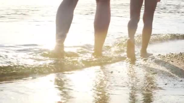 Papà e le gambe del bambino piedi camminando sull'acqua della spiaggia attraverso i raggi del sole. Vacanze estive, vacanze, viaggi in famiglia — Video Stock