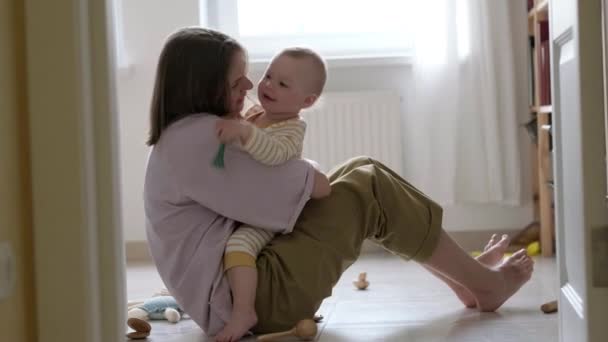 Klein meisje en mama die thuis op de vloer spelen. Moeder en dochter lachen samen plezier — Stockvideo