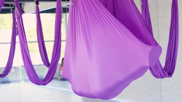 Slappna av. Ung kvinna övar i luftburen stretching swing. Flygande yoga övningar i lila hängmatta i fitnessklubben — Stockvideo