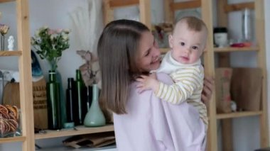 Küçük çocuk gülüyor, eğleniyor ve kameraya bakıyor. Mutlu Neşeli Aile. Anne ve Bebek Öpüşmesi.