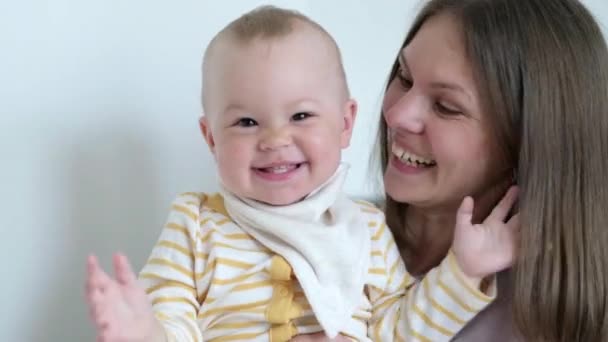 Kleines Kind, das lacht, Spaß hat und in die Kamera schaut. Frohe fröhliche Familie. Mutter und Baby küssen. — Stockvideo