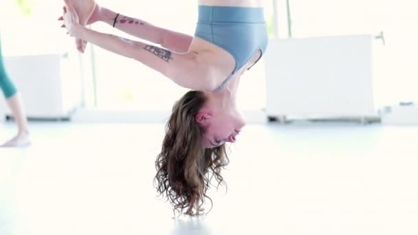 年轻女子练习空中伸展秋千。空中飞行瑜伽练习在健身俱乐部的紫色吊床上进行。2021年5月28日圣彼得堡俄罗斯 — 图库视频影像