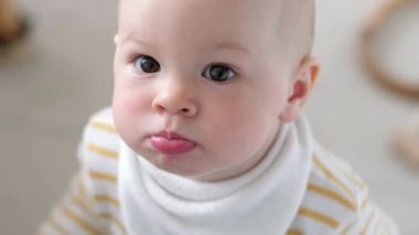 Evdeki meraklı çocuğun portresi. Küçük bebek mutfaktaki masadan dışarı bakar ve kameraya bakar. Mutlu çocukluk, evde oyunlar