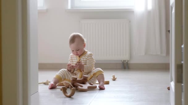 Eko Tahta Oyuncak Bebek Oyunu. Küçük zeki beyaz çocuk evde yerde doğal oyuncaklar oynuyor. Erken gelişim için eğitici oyunlar. Küçük çocuk oyuncağı ağzına koyar. — Stok video