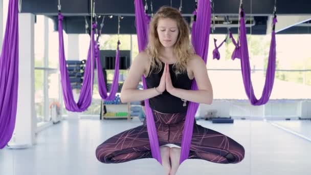 Retrato jovem sorridente mulher prática em aero alongamento swing. Exercícios de ioga de voo aéreo praticam em rede roxa no clube de fitness. 28maio2021 St.Petersburg Rússia — Vídeo de Stock