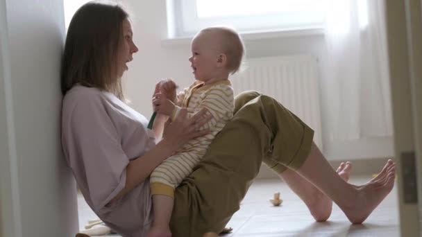 Klein meisje en mama die thuis op de vloer spelen. Moeder en dochter lachen samen plezier — Stockvideo