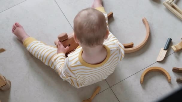 Draufsicht Öko-Holz Spielzeug Baby-Spiel. Kleines schlaues kaukasisches Kind, das zu Hause auf dem Fußboden mit Naturspielzeug spielt. Lernspiele für die frühe Entwicklung. — Stockvideo