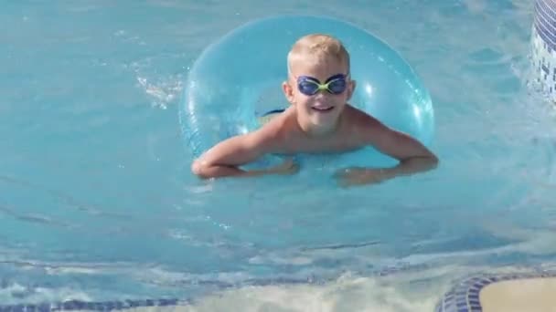 Retrato niño sonriente en piscina, niño en gafas de natación y círculo de natación. Vacaciones o clases en hoteles de verano. — Vídeo de stock