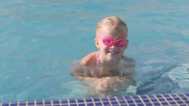 Menina sorridente retrato na piscina, criança em copos de natação e mangas infláveis. Viagens de verão férias ou aulas de hotel. Espaço de cópia. — Vídeo de Stock