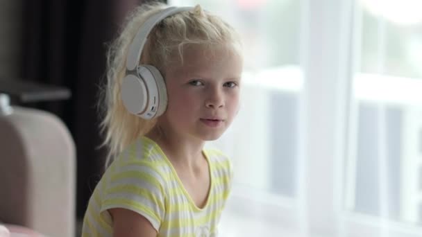 Porträtt vacker leende flicka i hörlurar. Barn som lyssnar på musik. vila, avkoppling, lugn tid för dig själv hemma — Stockvideo
