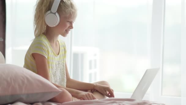 Blonďatá školačka studuje doma v posteli a dělá domácí úkoly s laptopem. Vzdálenost učení on-line vzdělávání. Zpátky do školy — Stock video