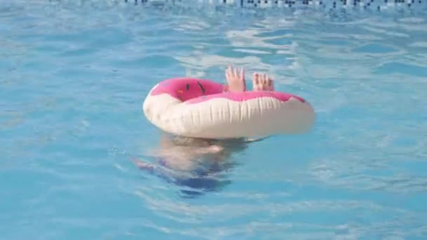 Chica en la piscina, niño divirtiéndose, sentado en el anillo de natación rosado donut, jugando bajo el agua. Verano viajes familia hotel vacaciones turistas. — Vídeo de stock