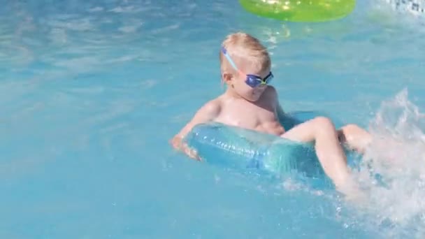 Menino na piscina, criança se divertindo, sentado no anel de natação azul, brincando debaixo d 'água. Viagens de verão família hotel férias turistas. — Vídeo de Stock