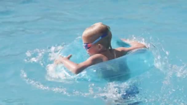 Niño en la piscina, niño divirtiéndose, sentado en el anillo de natación azul, jugando bajo el agua. Verano viajes familia hotel vacaciones turistas. — Vídeo de stock