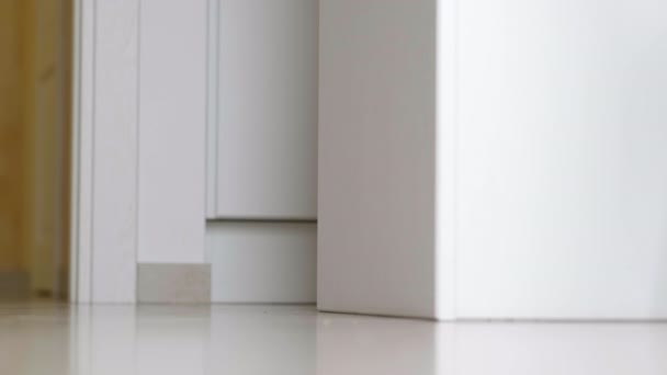 Niño dando los primeros pasos. Niña irreconocible caminando en el suelo blanco en casa. piernas descalzas en la cocina. — Vídeos de Stock