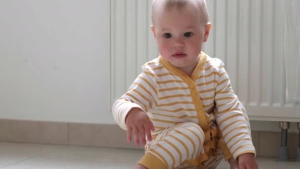 Baby boy taking first steps . Little child girl walking on gets up and starts walking at home. Barefoot legs on kitchen. — Stock Video