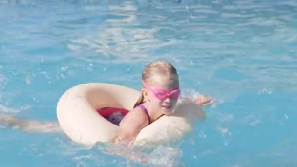 Niña pequeña en la piscina, niño divirtiéndose, sentado en el anillo de natación azul, jugando bajo el agua. Verano viajes familia hotel vacaciones turistas. — Vídeo de stock