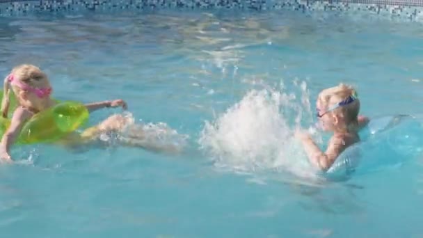 Niño y niña nadando en la piscina, niños divirtiéndose, salpicando agua. Verano viajes familia hotel vacaciones turistas. — Vídeo de stock