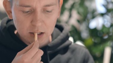 Ağzını kapat. Erkek öğrenci fast food restoranında patates kızartması yiyor ve kola içiyor. Sağlıksız beslenme, abur cubur, abur cubur