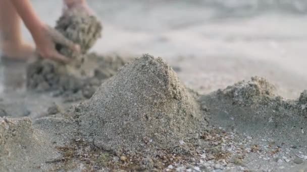 Egy szőke kisfiú, aki homokkal játszik a tengerparton. Homokvárat építenek. Családi nyaralás és kirándulások a meleg országokban. — Stock videók