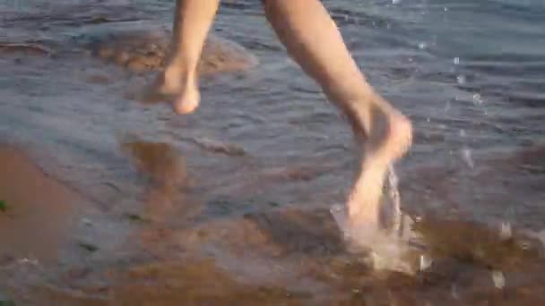 Piedi delle gambe del bambino che corrono sull'acqua della spiaggia attraverso i raggi del sole. Vacanze estive, vacanze, viaggi in famiglia — Video Stock