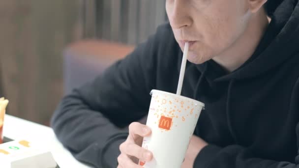 Homem estudante bebe Coca-cola no restaurante de fast food McDonalds. Nutrição insalubre, lanches, junk food. 26aug2021 São Petersburgo Rússia — Vídeo de Stock