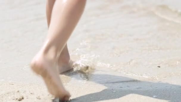 Kleiner Junge geht ins Meer. Babybeine Füße, die auf Strandwasser gehen. Sommerurlaub, Urlaub, Familienausflug in warme Länder — Stockvideo