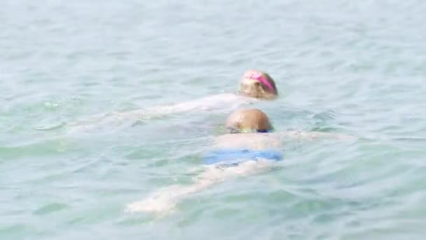 Мальчик и девочка плавают в морской воде, дети веселятся, играют и брызгают. Летние каникулы, отдых, семейная поездка в теплые страны — стоковое видео