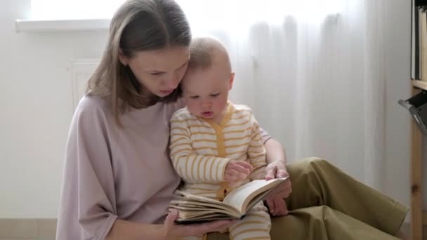 Äiti ja vauva sonreading kirjan sängyssä ennen nukkumaanmenoa. Perheen rakkauden aikaa yhdessä — kuvapankkivideo
