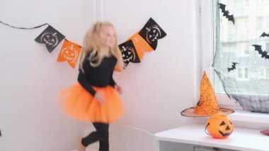 4 bin. Cadılar Bayramı çocukları. Cadı kostümlü küçük sarışın kız evde dans ediyor, yatakta zıplıyor. Tatile hazırım.