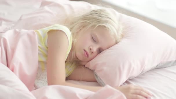 Menina loira adorável dormindo docemente pela manhã em roupa de cama rosa em casa. Sonhos infantis, conforto, descanso e paz — Vídeo de Stock