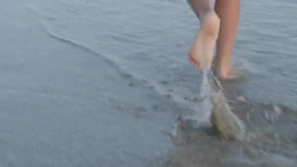 Babybeine Füße laufen auf dem Strandwasser durch die Sonnenstrahlen. Sommerurlaub, Urlaub, Familienausflug — Stockvideo