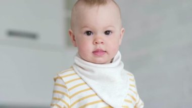 Evdeki meraklı çocuğun portresi. Küçük bebek gülümsüyor ve kameraya bakıyor. Mutlu çocukluk, evde oyunlar