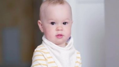 Evde mutfakta dans eden küçük bebek cep telefonuyla çocuk şarkıları dinliyor. Mutlu çocukluk ve modern teknoloji.