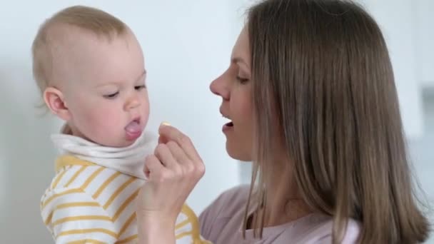Mam stopt vitamine in de mond van de kinderen. thuis baby 's eten. Gezond eten, snack of lunchtijd. — Stockvideo