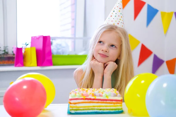 Dos niños caucásicos rubios chico y chica divirtiéndose y riendo en la fiesta de cumpleaños. Fondo colorido con globos y pastel de arco iris de cumpleaños . —  Fotos de Stock