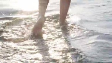 Çıplak ayaklı çocukların ayakları sahildeki okyanus suyunda yürüyor. Yaz tatili, tatil, aile gezisi. Sıcak ülkelere turizm