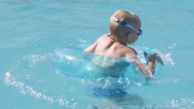 Yüzme havuzunda küçük bir çocuk, eğlenen bir çocuk, mavi yüzme ringinde oturuyor, suyun altında oynuyor. Yaz tatili aile tatili turistleri.