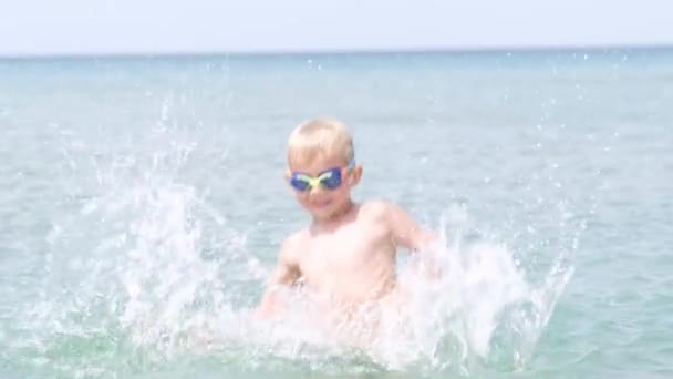 Портрет счастливый улыбающийся мальчик, играющий в океанской морской воде, ребенок веселится, плавает и брызгает. Летние каникулы, отдых, семейная поездка в теплые страны — стоковое видео