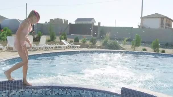 Back view happy girl running and jumping in swimming pool, children having fun, splashing water. Summer travel family hotel vacation tourists. — Stock Video