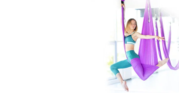 Banner Luchtvaart yoga oefeningen. Portret jonge glimlachende vrouw praktijk in aero stretching swing in paarse hangmat in fitness club. Kopieerruimte — Stockfoto