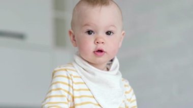 Evdeki meraklı çocuğun portresi. Küçük bebek gülümsüyor ve kameraya bakıyor. Mutlu çocukluk, evde oyunlar