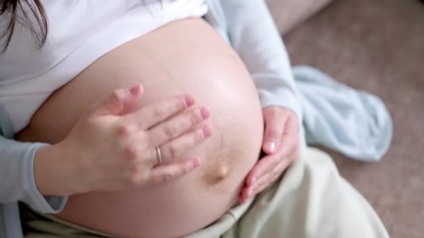 4k Schwangere werdende Mutter streichelt ihren Bauch. Die Hände der Frau berühren ihren Bauch, das wartende Kind. Vorbereitung auf die Geburt, Mädchen mit dickem Bauch fortgeschrittene Schwangerschaft. — Stockvideo