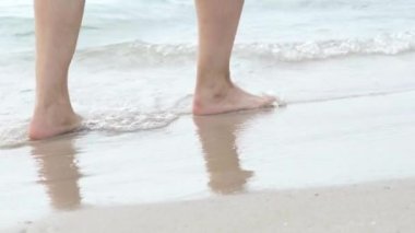 Çıplak ayaklı adam ayakları sahildeki okyanus suyunda yürüyor. Yaz tatili, tatil, aile gezisi. Sıcak ülkelere turizm